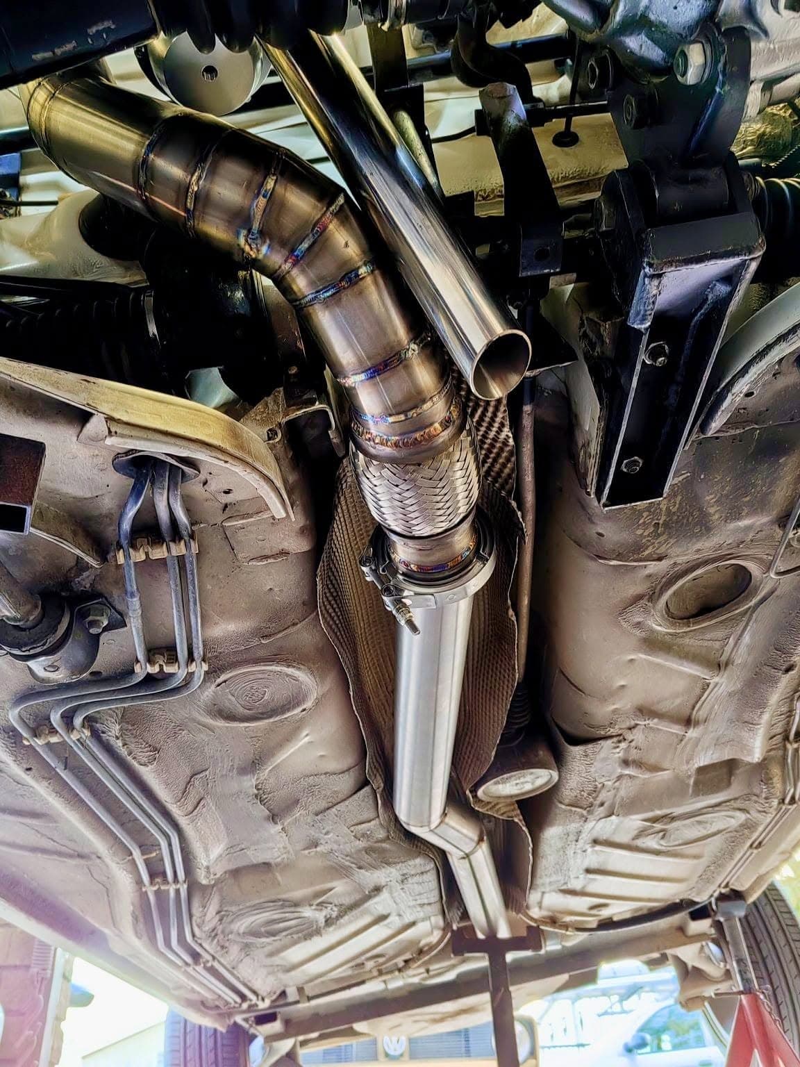 Custom stainless downpipe installed beneath a vehicle