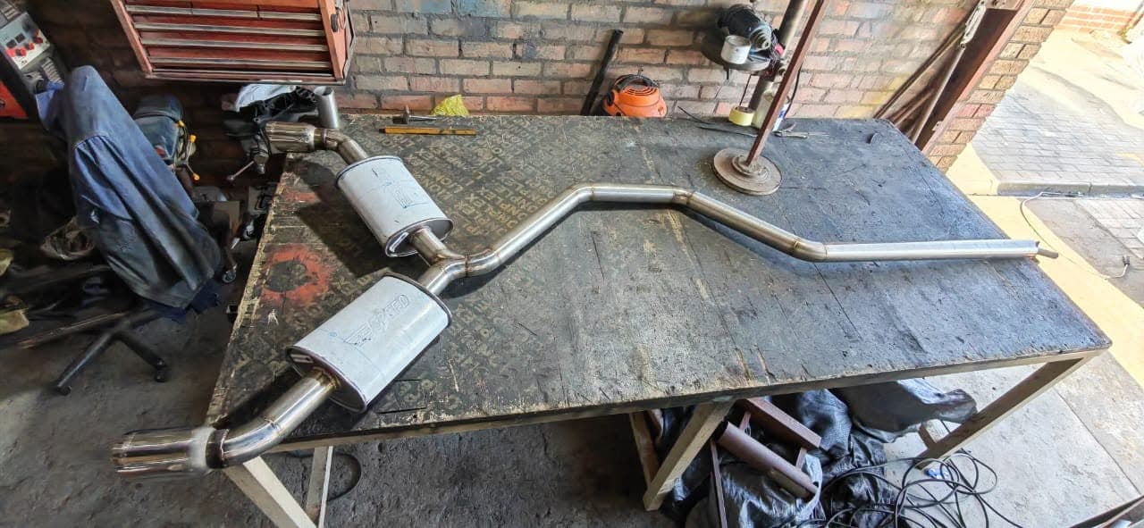 Complete Golf 7 GTI stainless exhaust with twin boxes and polished tips on the workshop bench