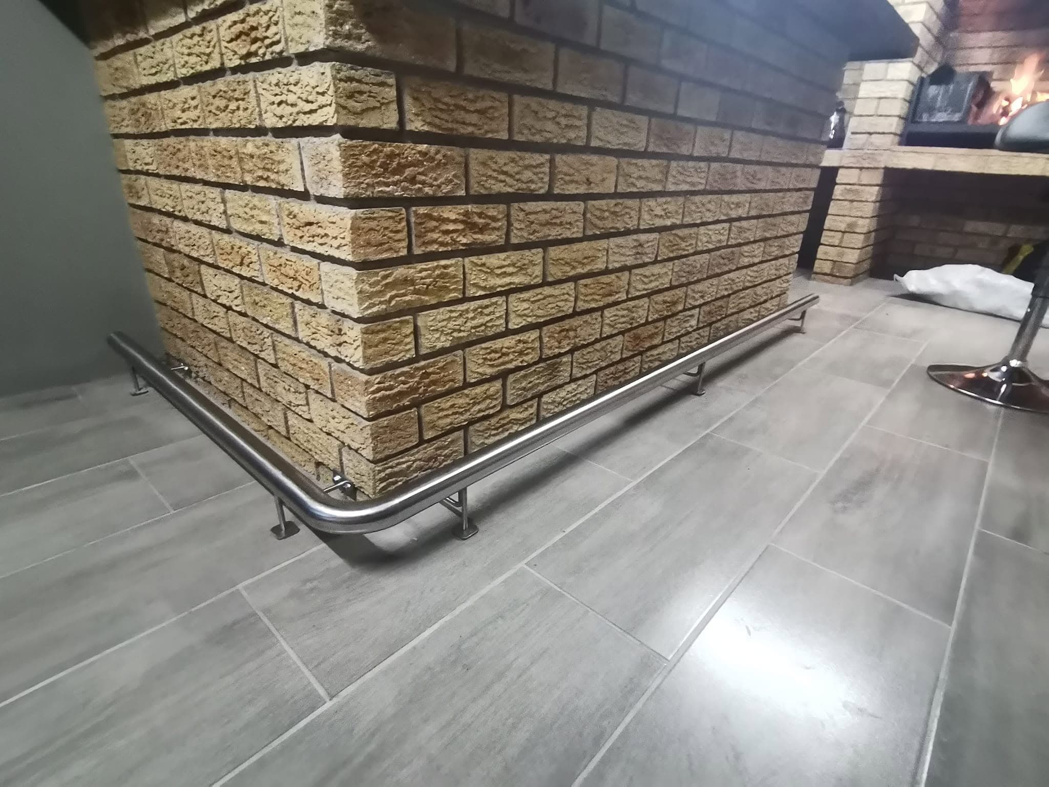 Stainless steel foot rail installed around a brick home bar